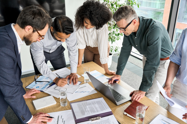 Team standing over a table looking at plans