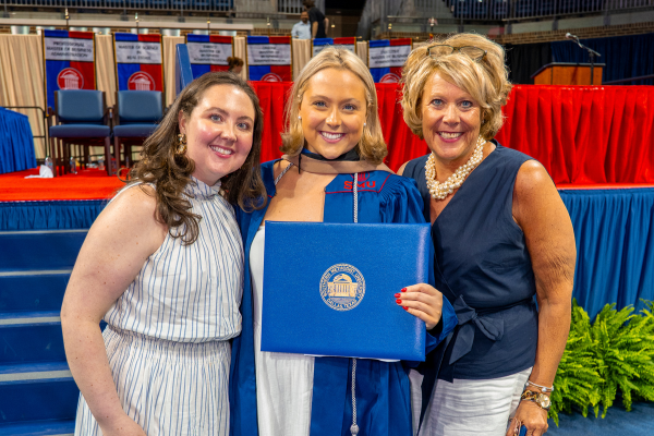 Graduate holds diploma with sister and mother