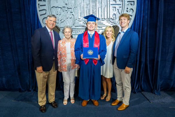 graduate and family in front of SMU seal