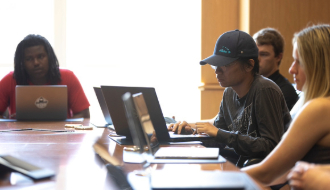 Photos of students of the operations club sitting around a conference table