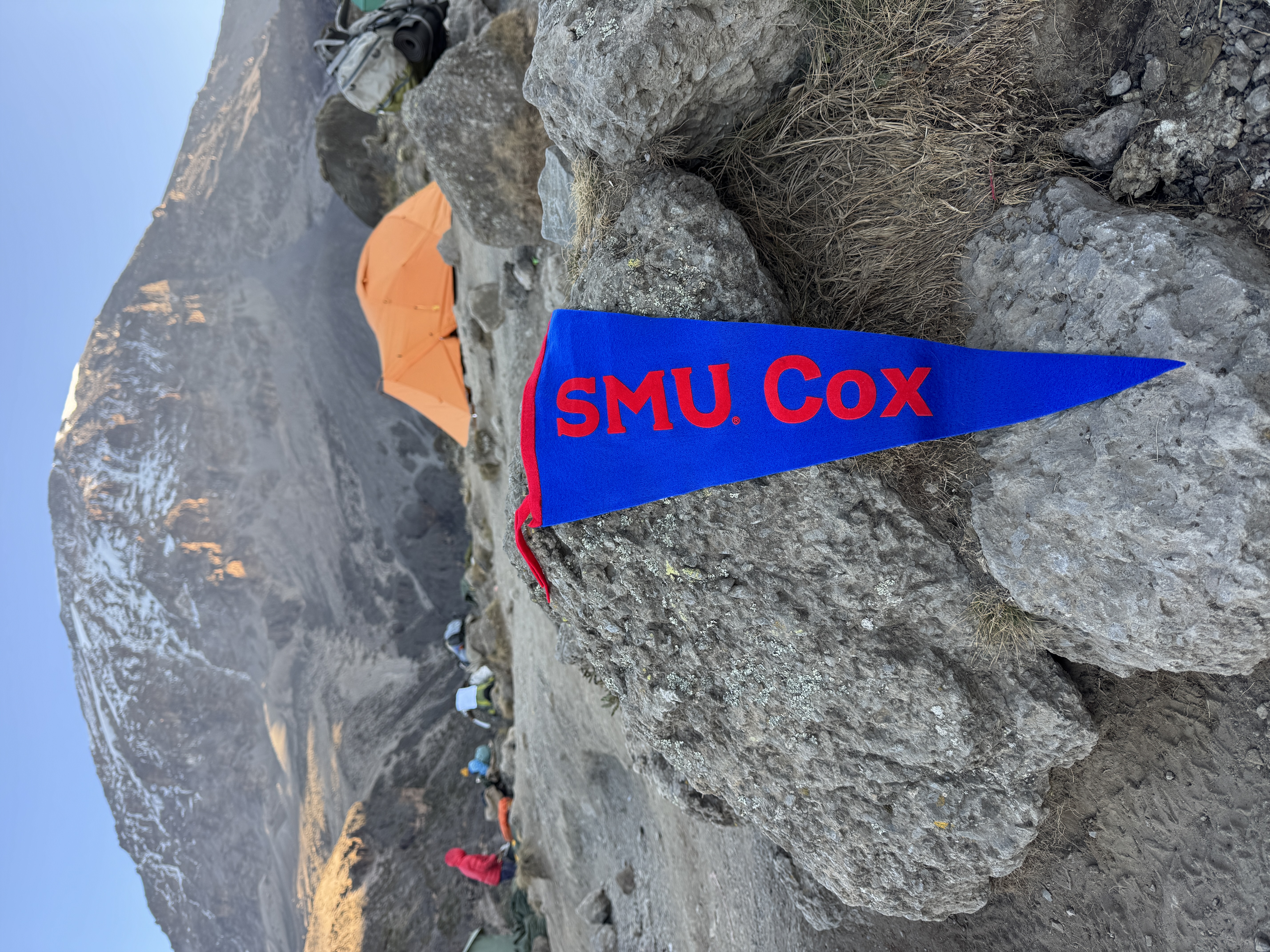 SMU Cox banner draped on a boulder on Mount Kilimanjaro