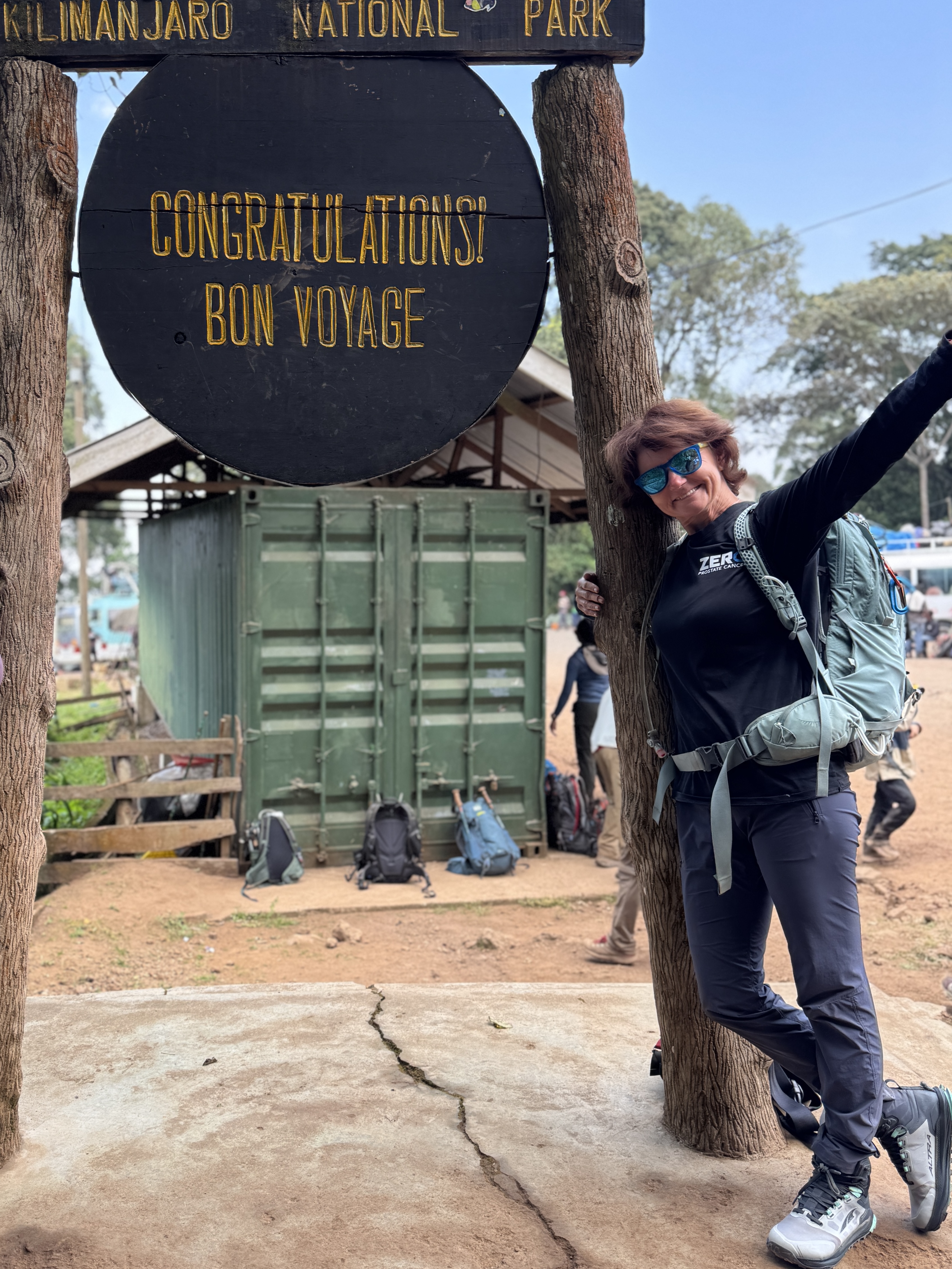 Angelika Leskovskaya poses with a sign at Kilimanjaro National Park that says "Congratulations, Bon Voyage" 