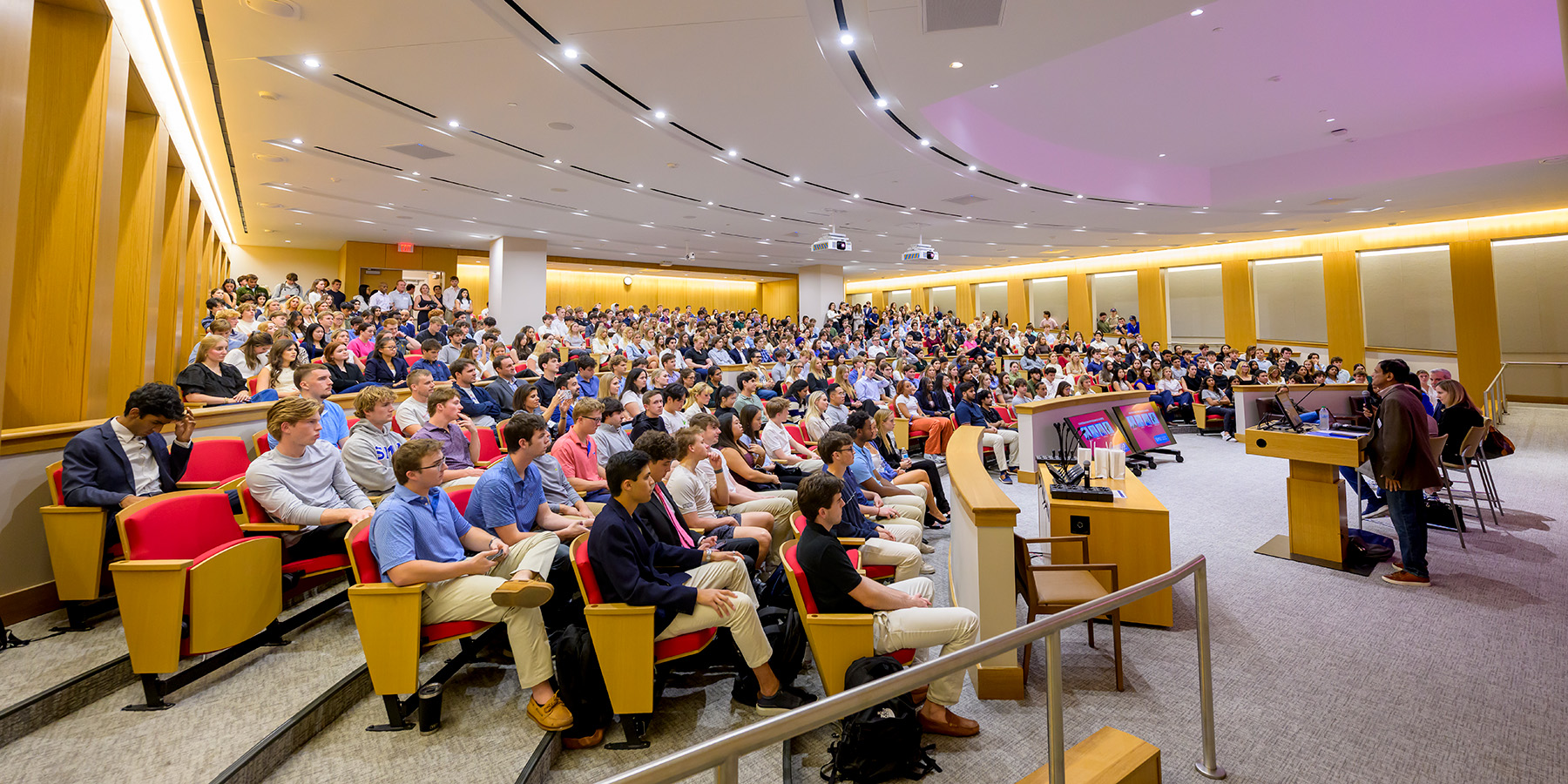 SMU Cox students sit in a classroom with stadium seating