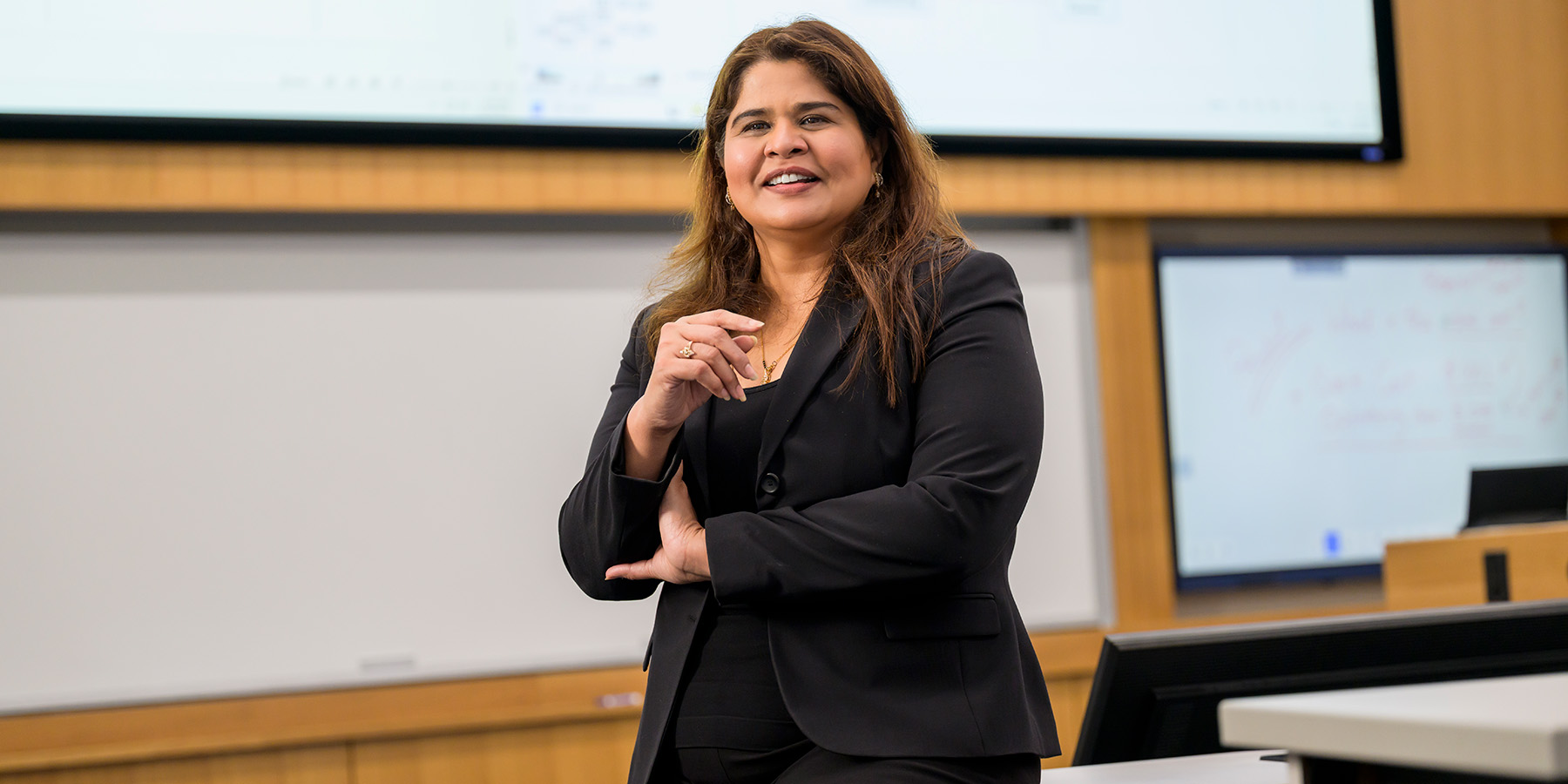 Gauri Bhat stands smiling at the front of a classroom