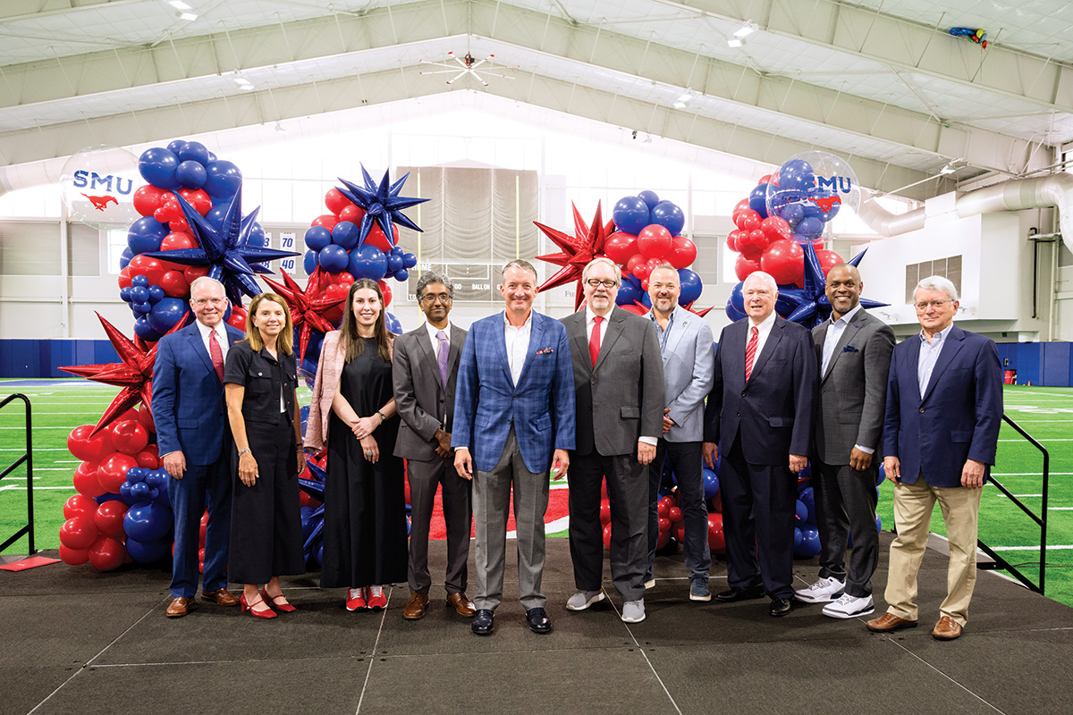 Dean Milbourn poses for a group shot with other SMU leaders in front of a red and blue balloon installation