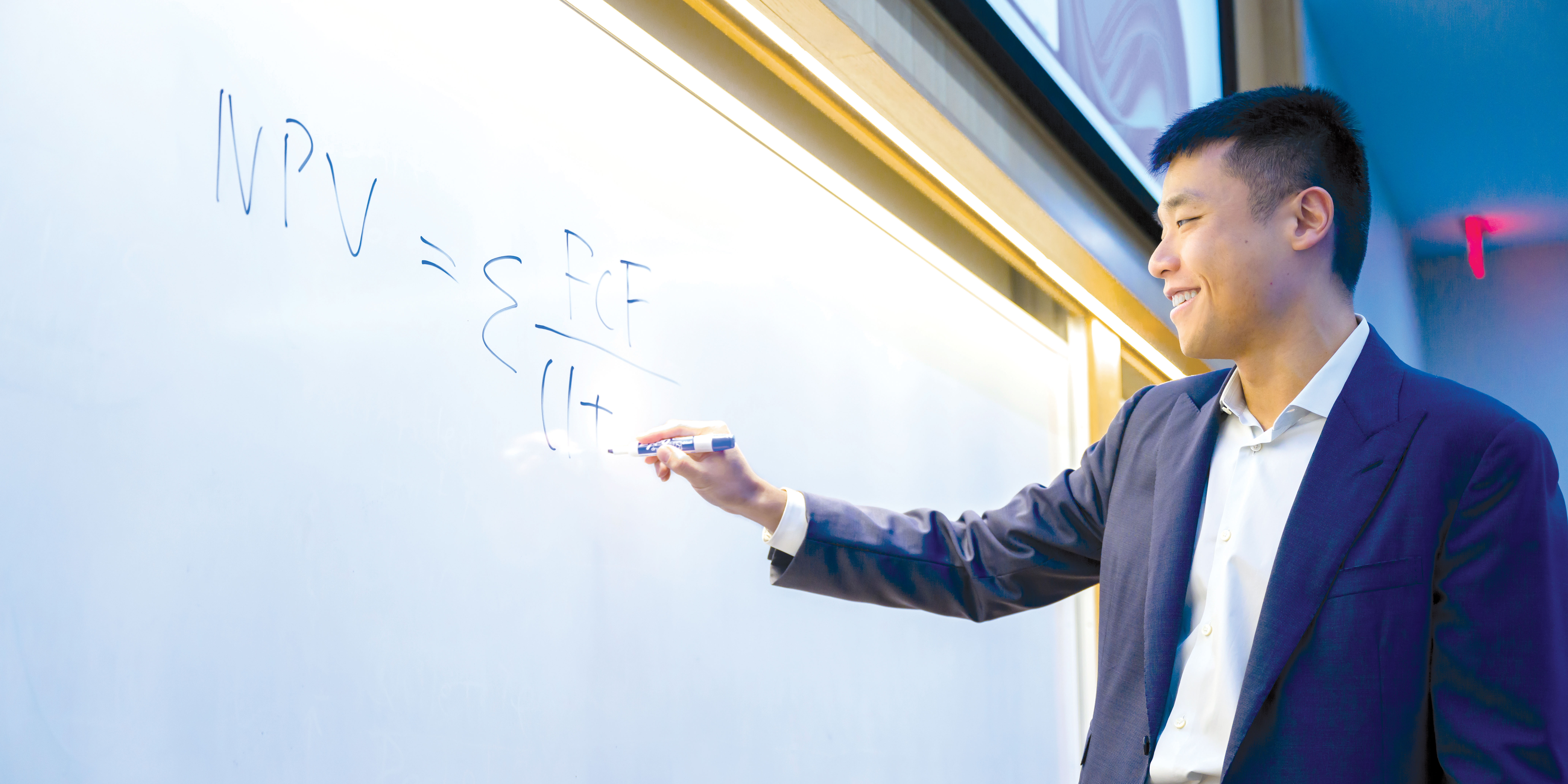 Huang smiles and writes an equation on a classroom whiteboard