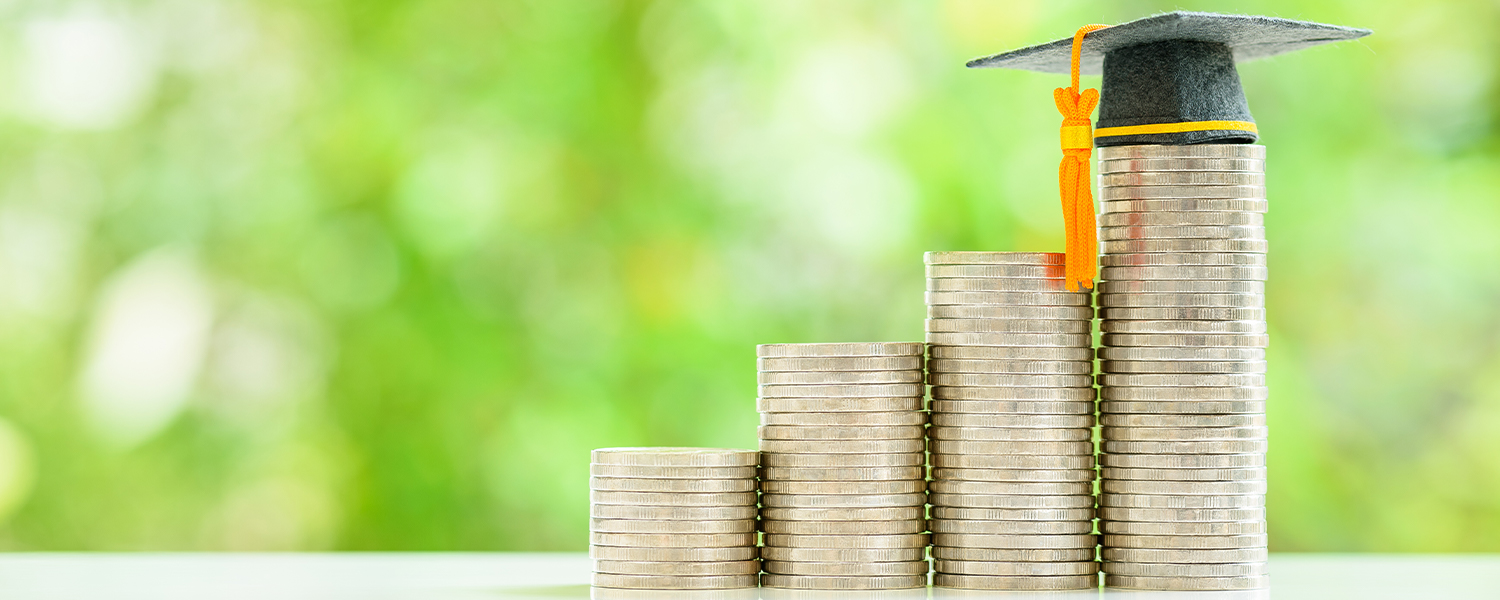A growing series of stacks of coins with a graduation cap on top of the largest stack of coins.