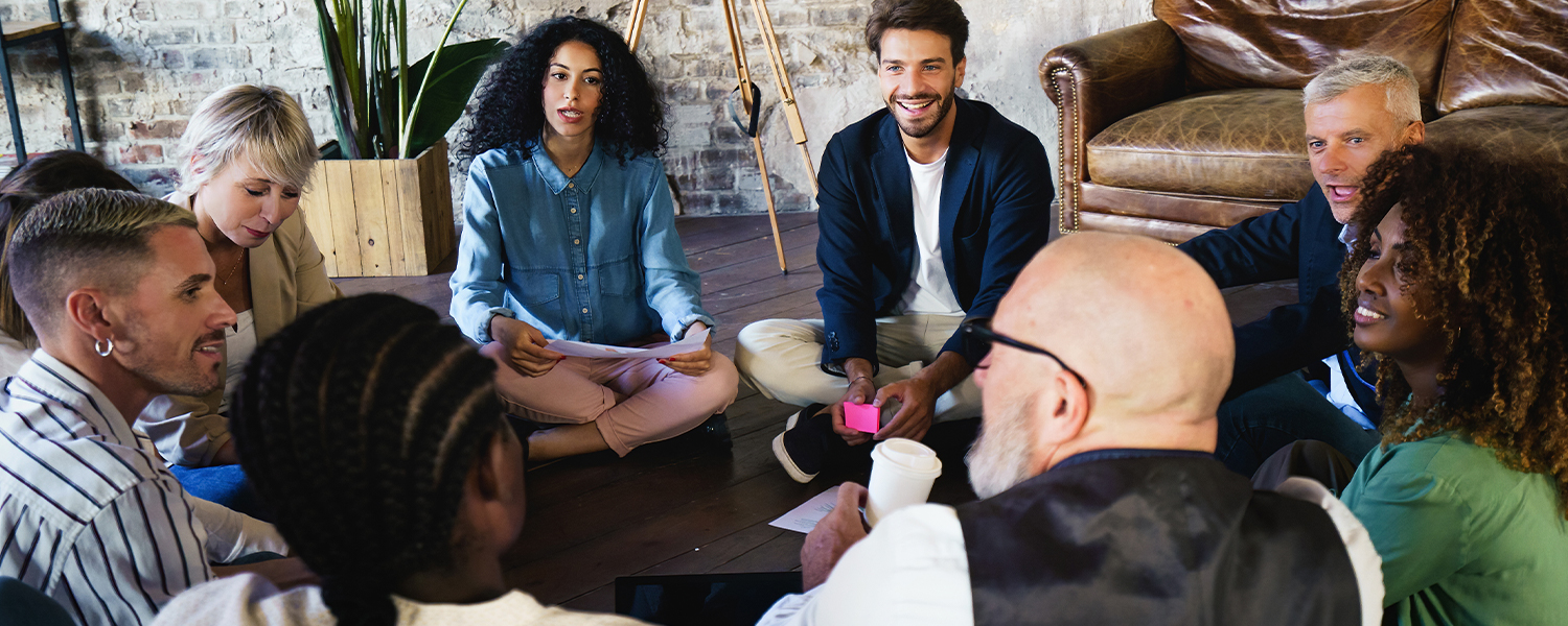 A diverse group of people sitting in a circle talking with each other.