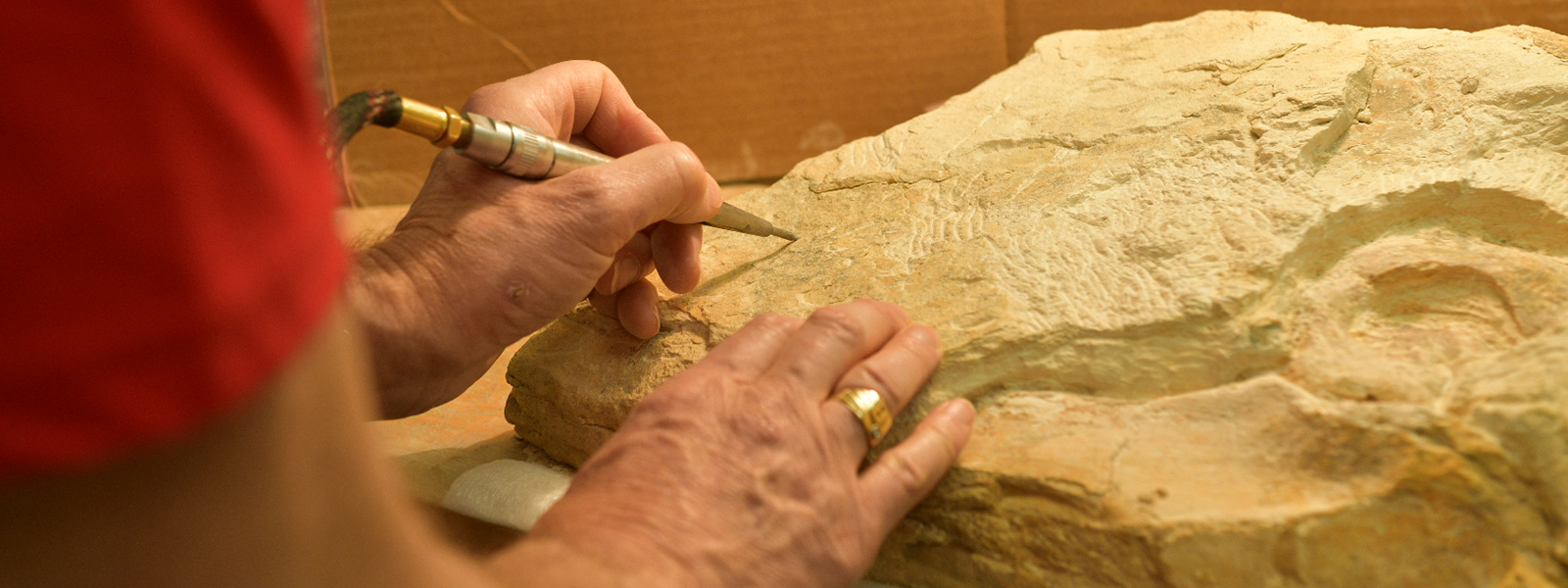 Person using tool working on a rock. 