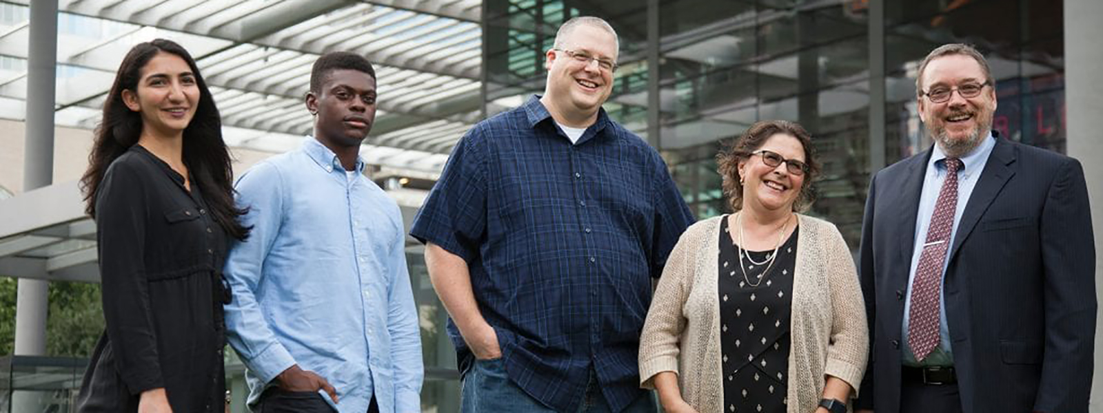 Group of people standing smiling at camera. 