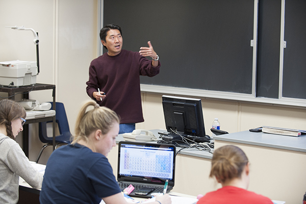 Persona t front of classroom lecturing. 