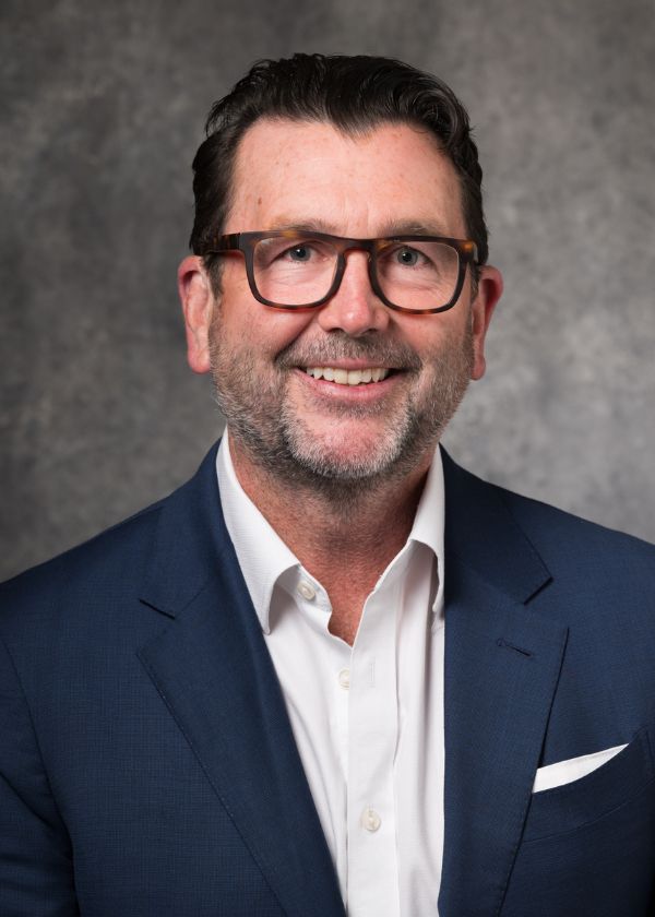 Photo of Chase Simmons in a white shirt and blue suit jacket