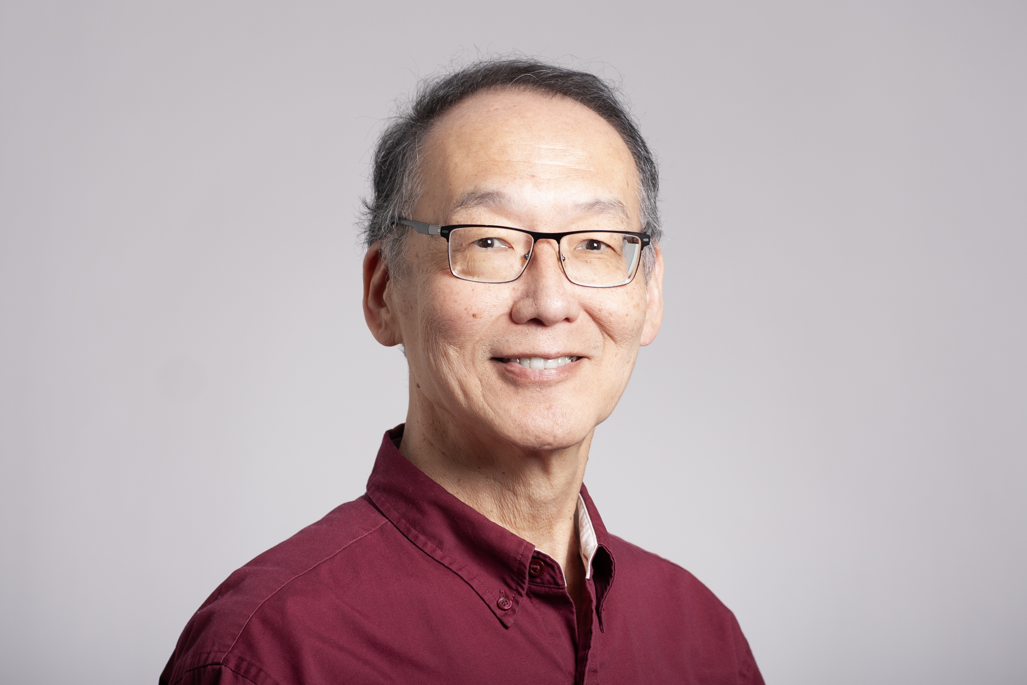 Portrai of research professor Tsengdar Lee wearing a red button up shirt