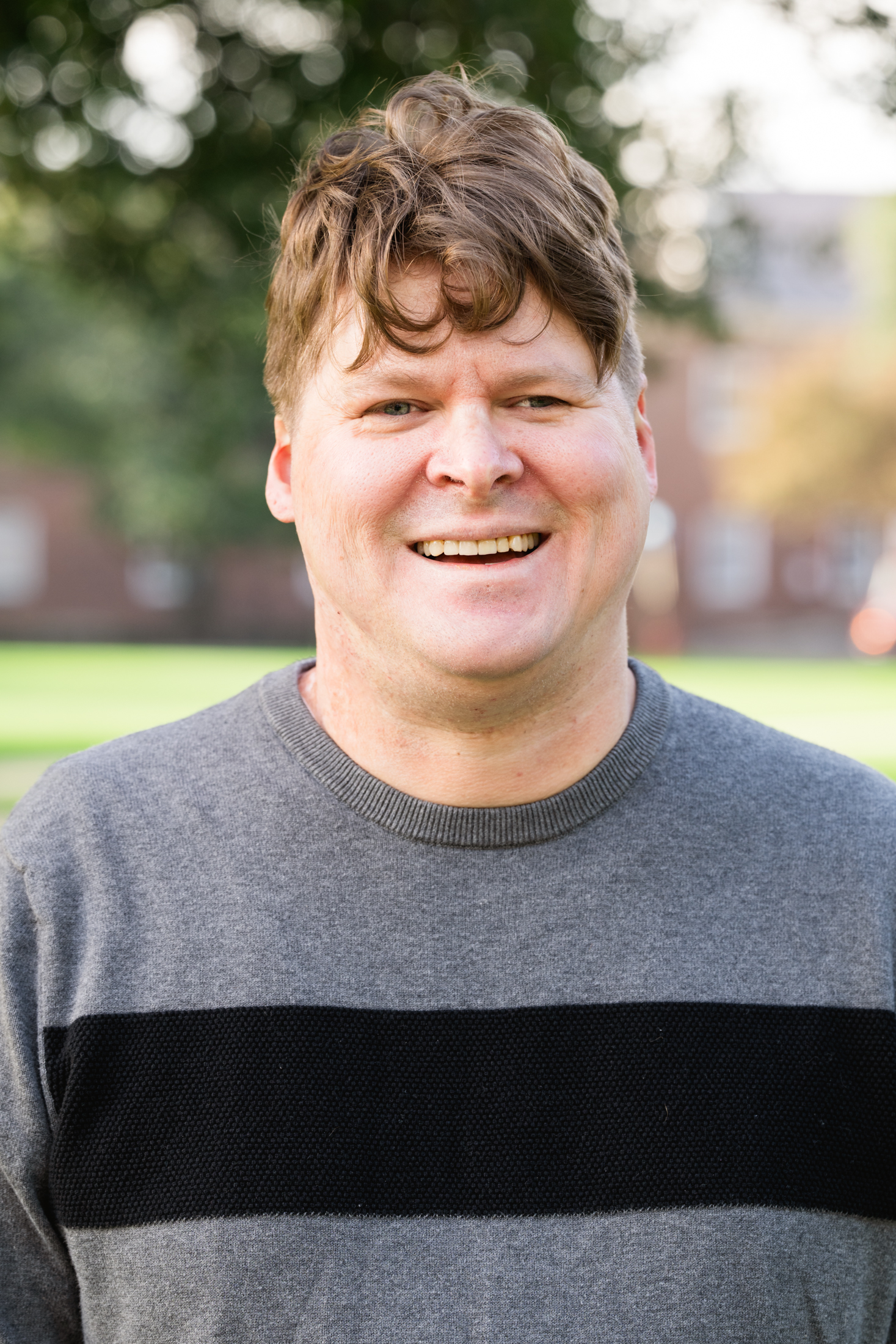 Photo of Philip Smith wearing a gray shirt with black horizontal stripe