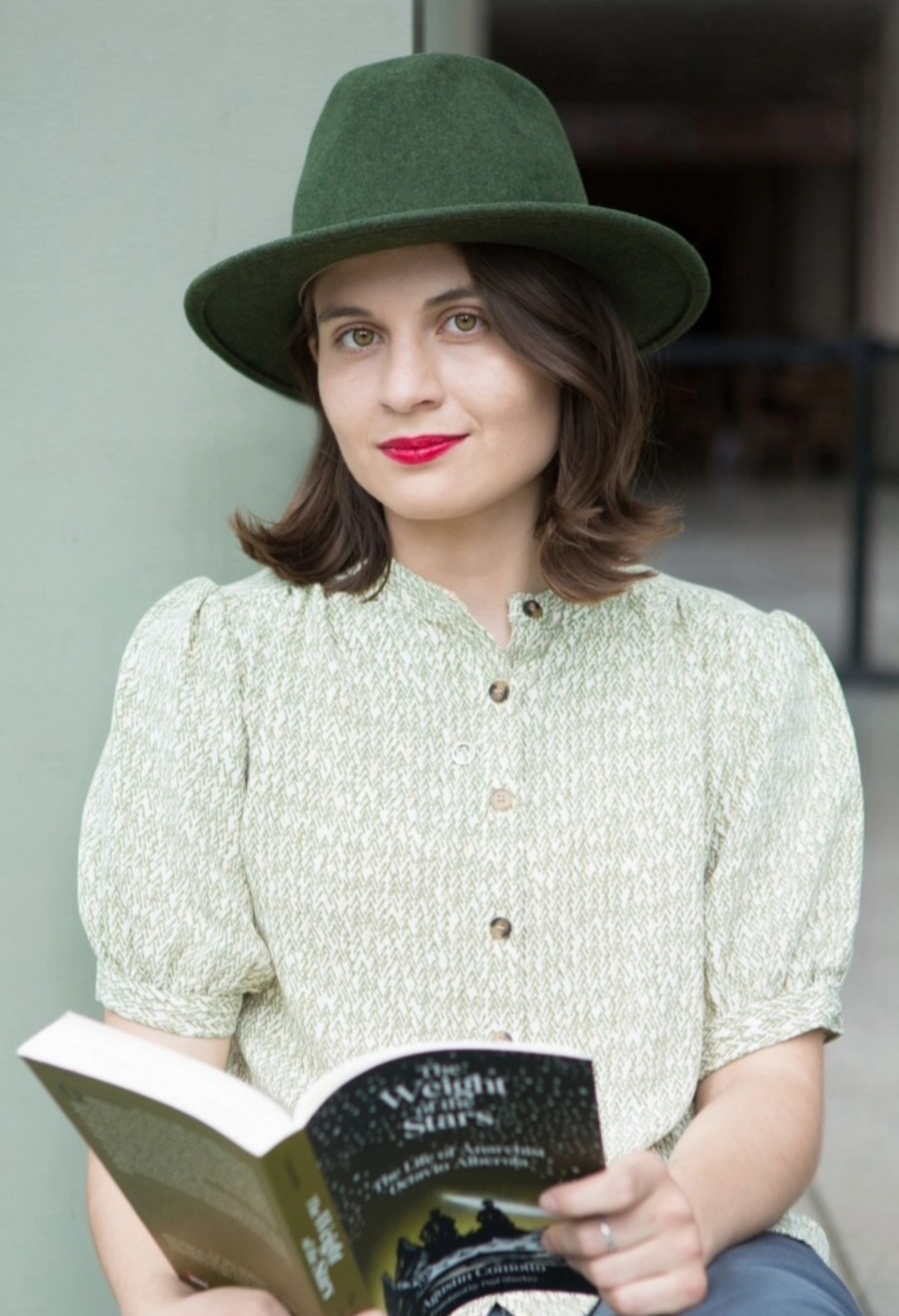 Arianna Peruzzi wearing a green felt hat and holding a book