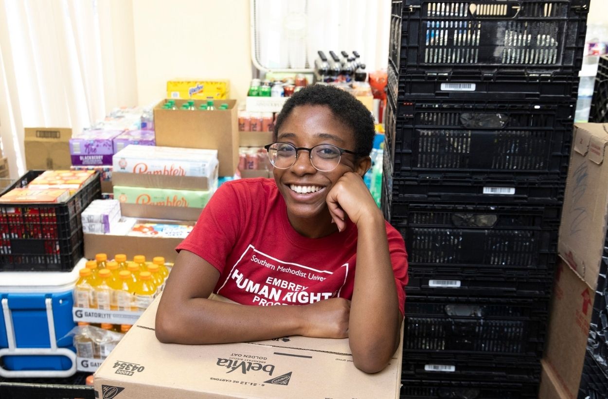 Undergraduate student Bailey Kamau leaning on a box in a food pantry
