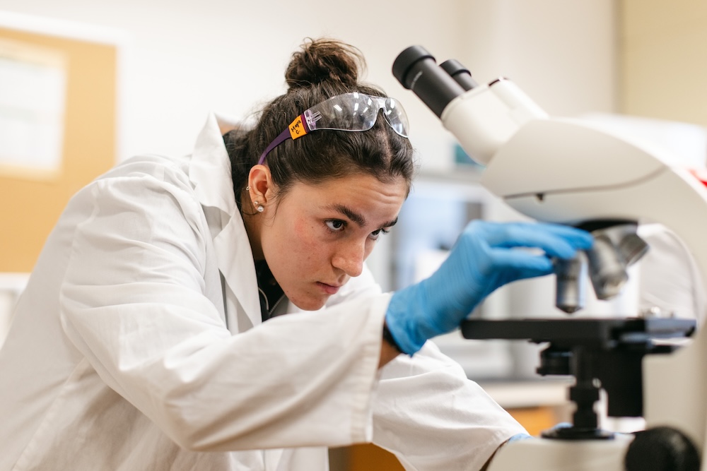 A graduate student in the biology masters program at SMU prepares to study a slide in a microscope.