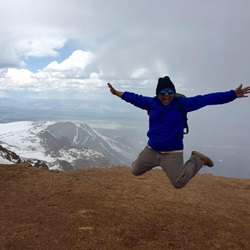 Astrud Villareal jumping in the air with a snow-capped mountain in the distance.