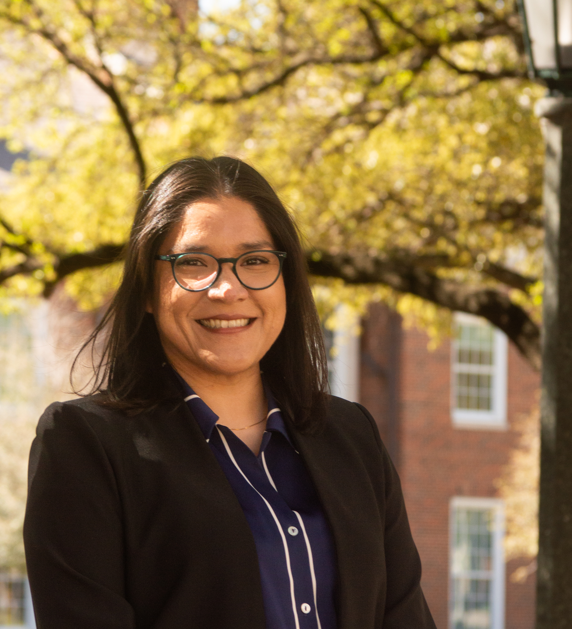 Eva Calvario wearing a black blazer standing outside among fall trees