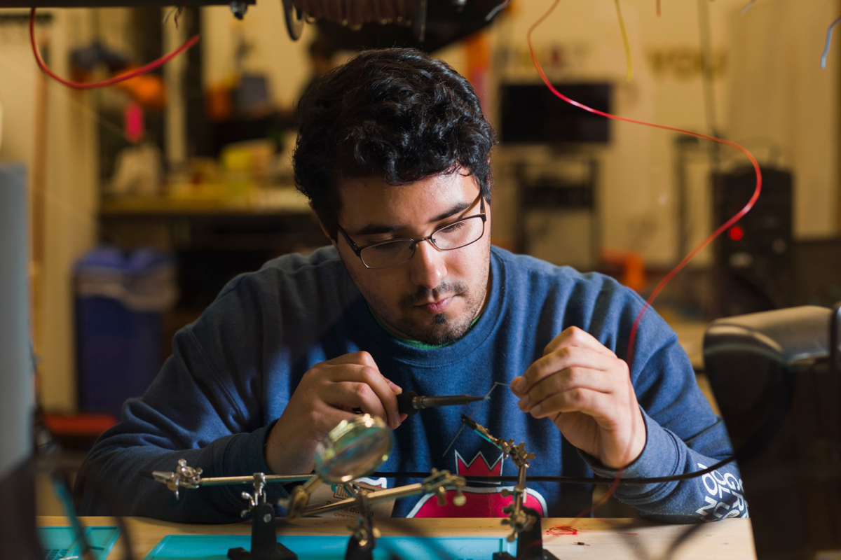A student uses a soldering iron on a small electrical device