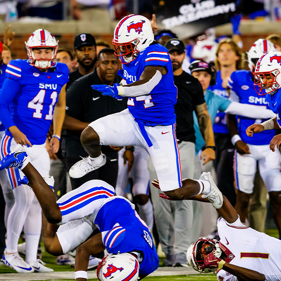 An SMU football player hurdles over another player during a football game. 