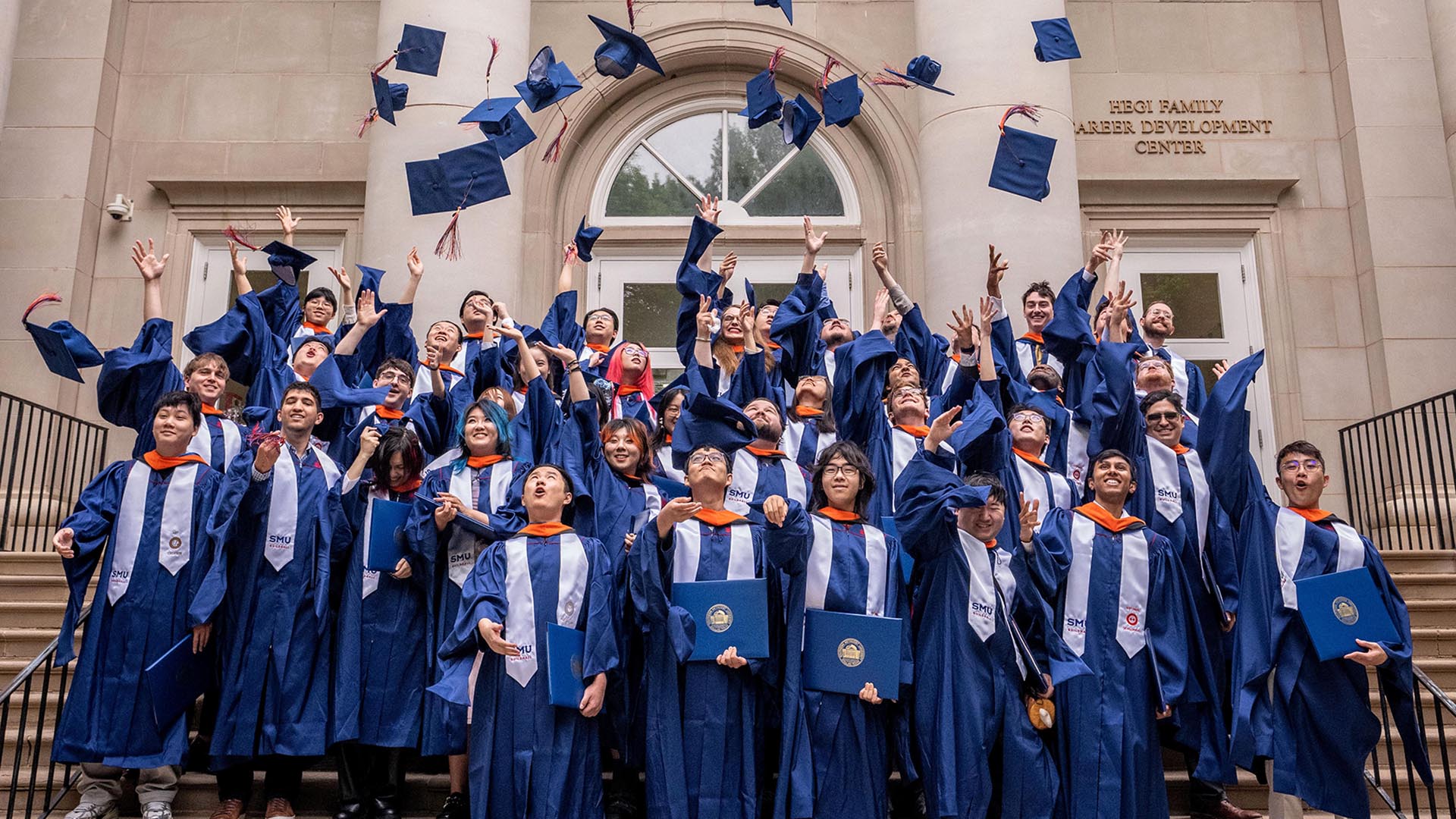 Photo of SMU Guildhall students tossing caps at graduation