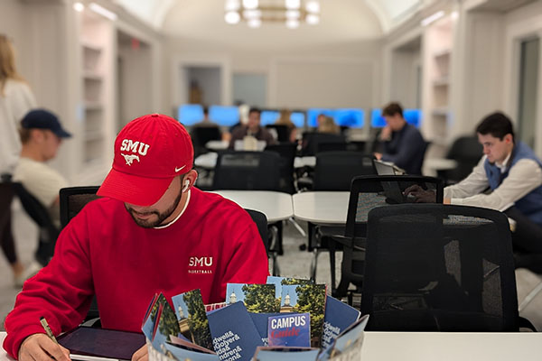 Student wearing red SMU cap studying at table in the Duda Family Business Library