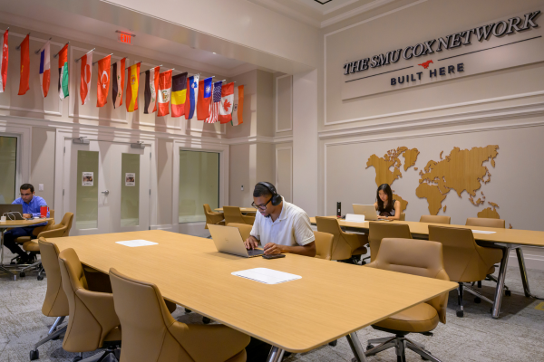 Students study in the Ida Family Reading Room with a world map and international flags on the walls.