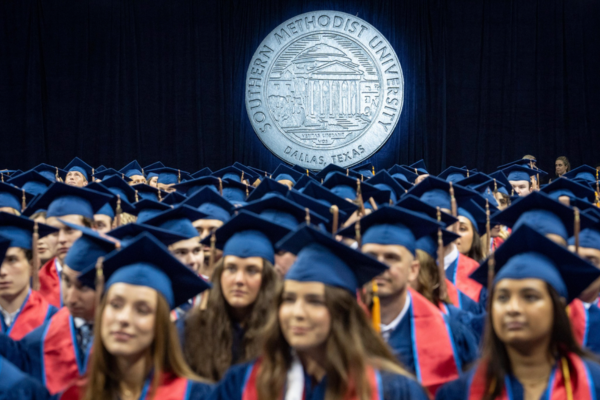 Cox grads sitting with SMU crest behind them