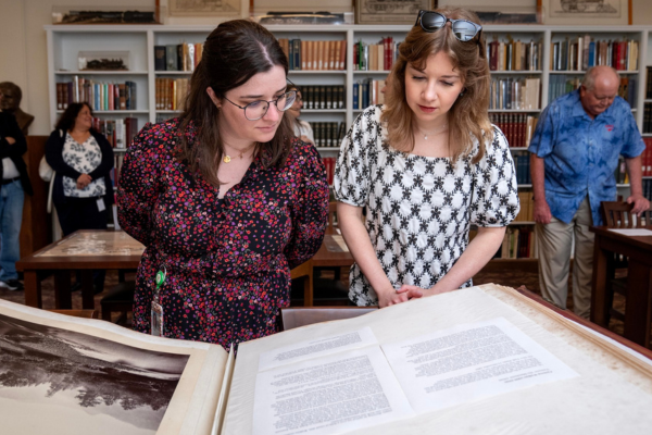 Two women look at a large book on display