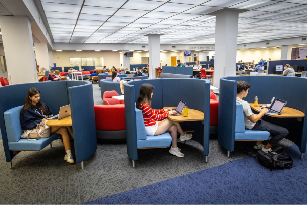 Three students in a row of single-person study desks