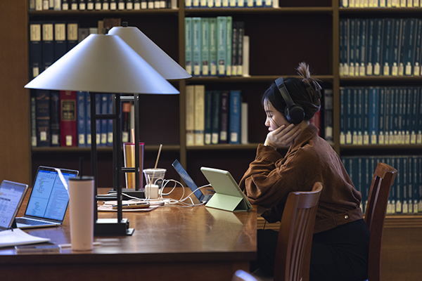 student wearing headphones studies alone in the Fondren Library Centennial Reading Room