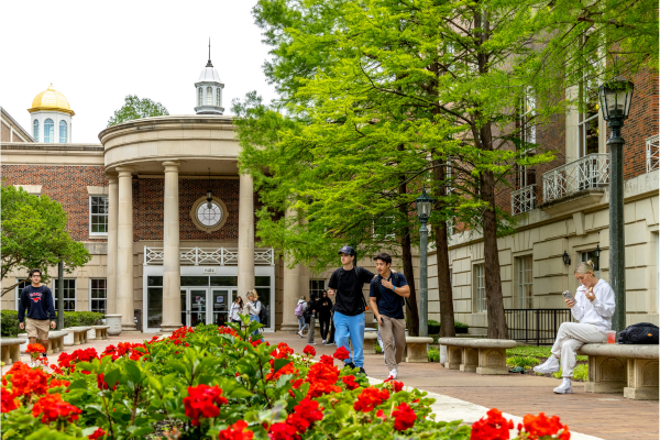The Fondren Library building with red flowers in the foreground