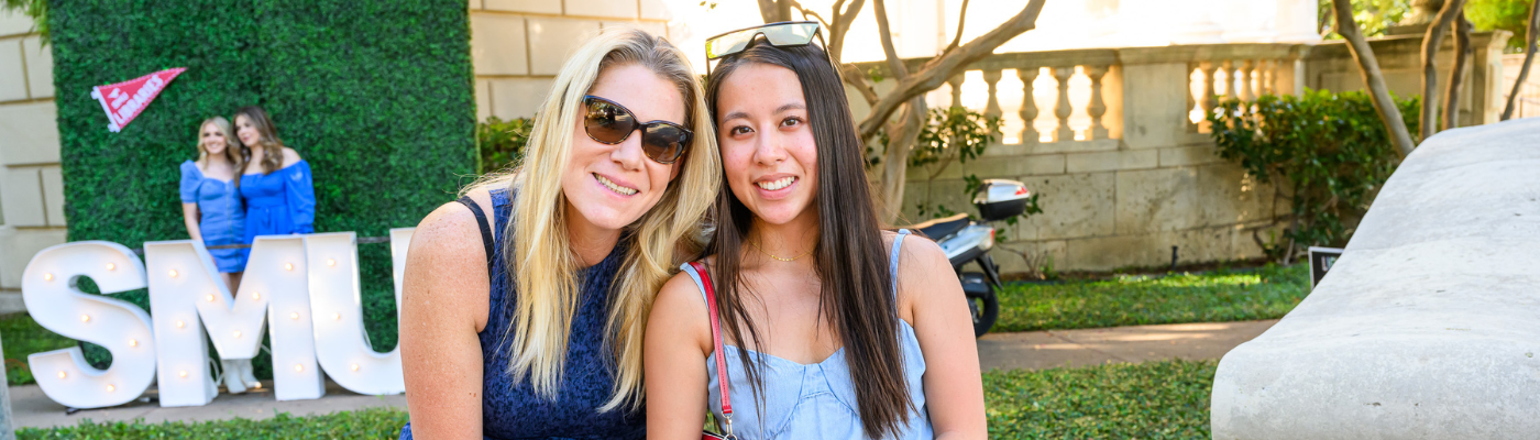 A student poses with her parent in front of Fondren Library during family weekend