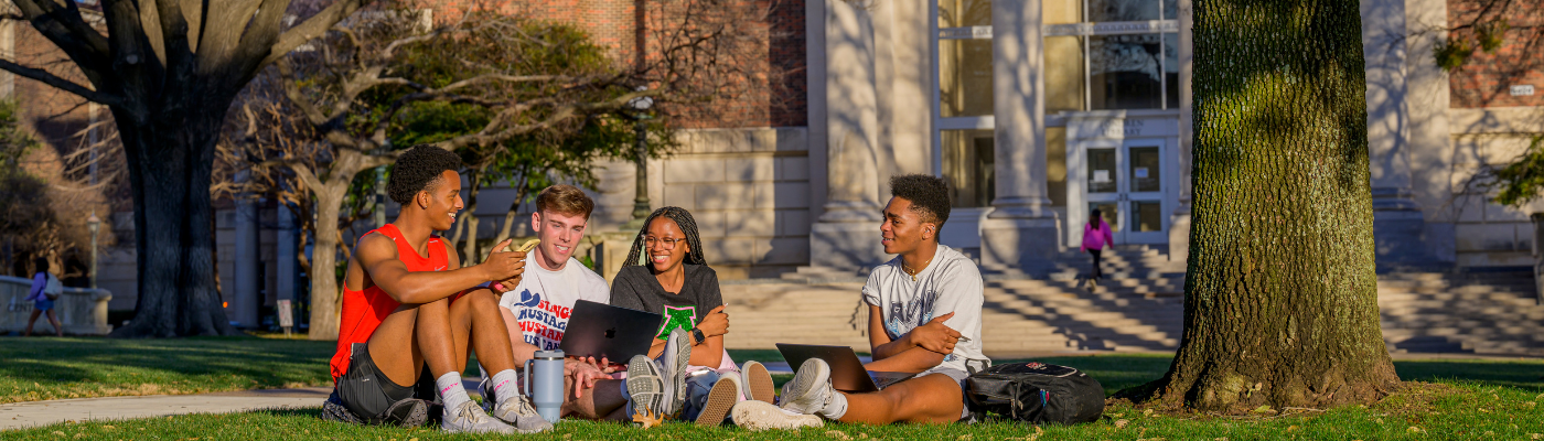 A group of students sitting on the lawn in front of Fondren Library