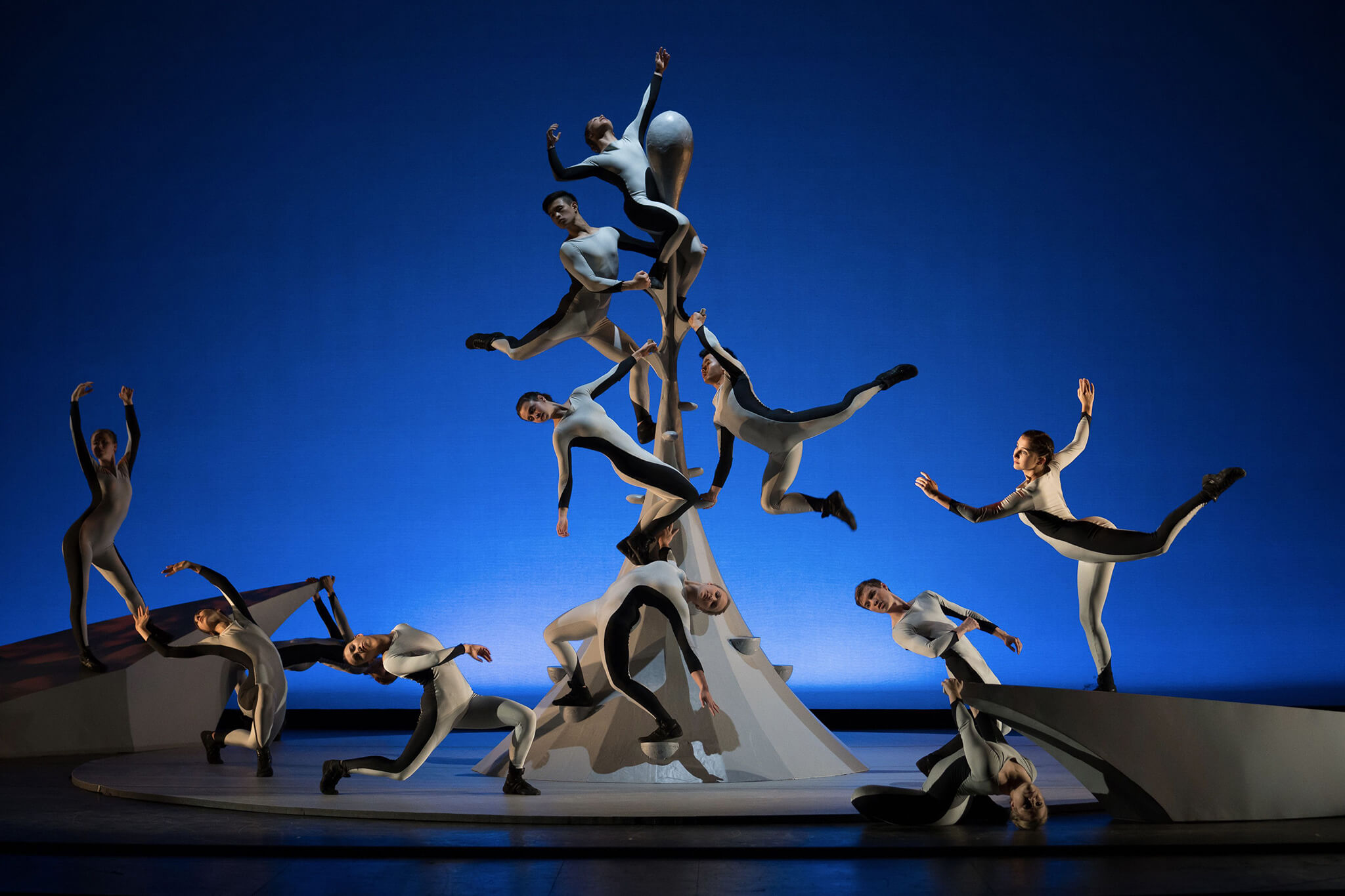 Dances in black in white on a stage against a blue background