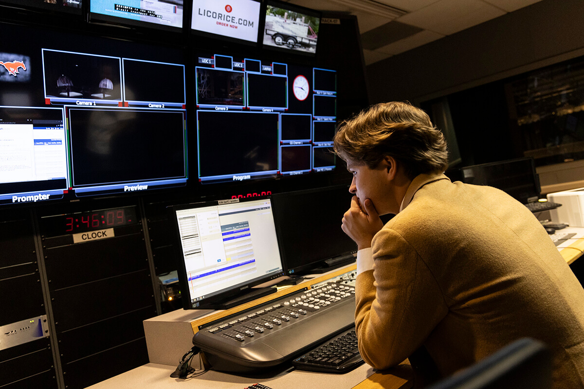 male student looking at a wall of monitors