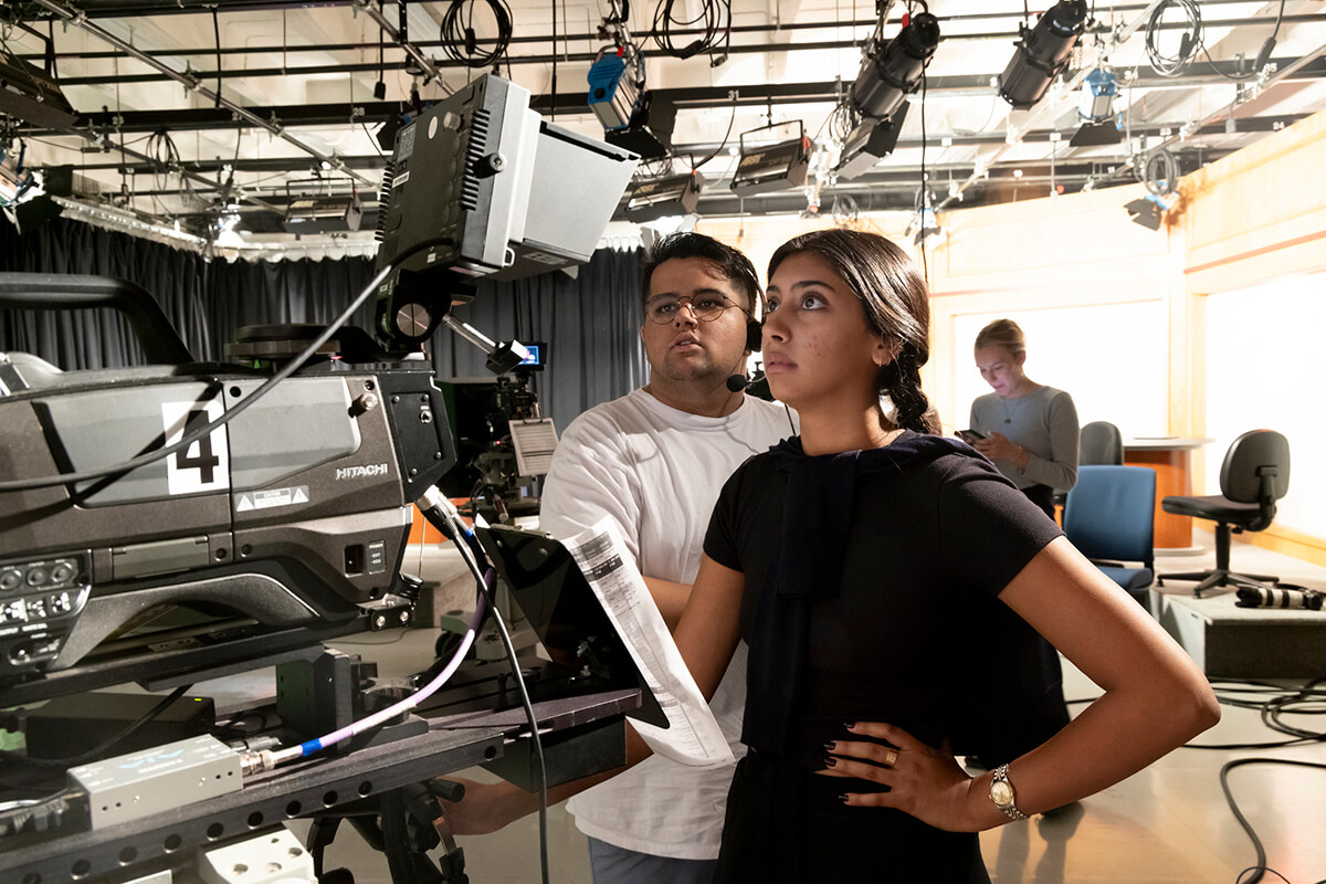 male and female student use a news camera