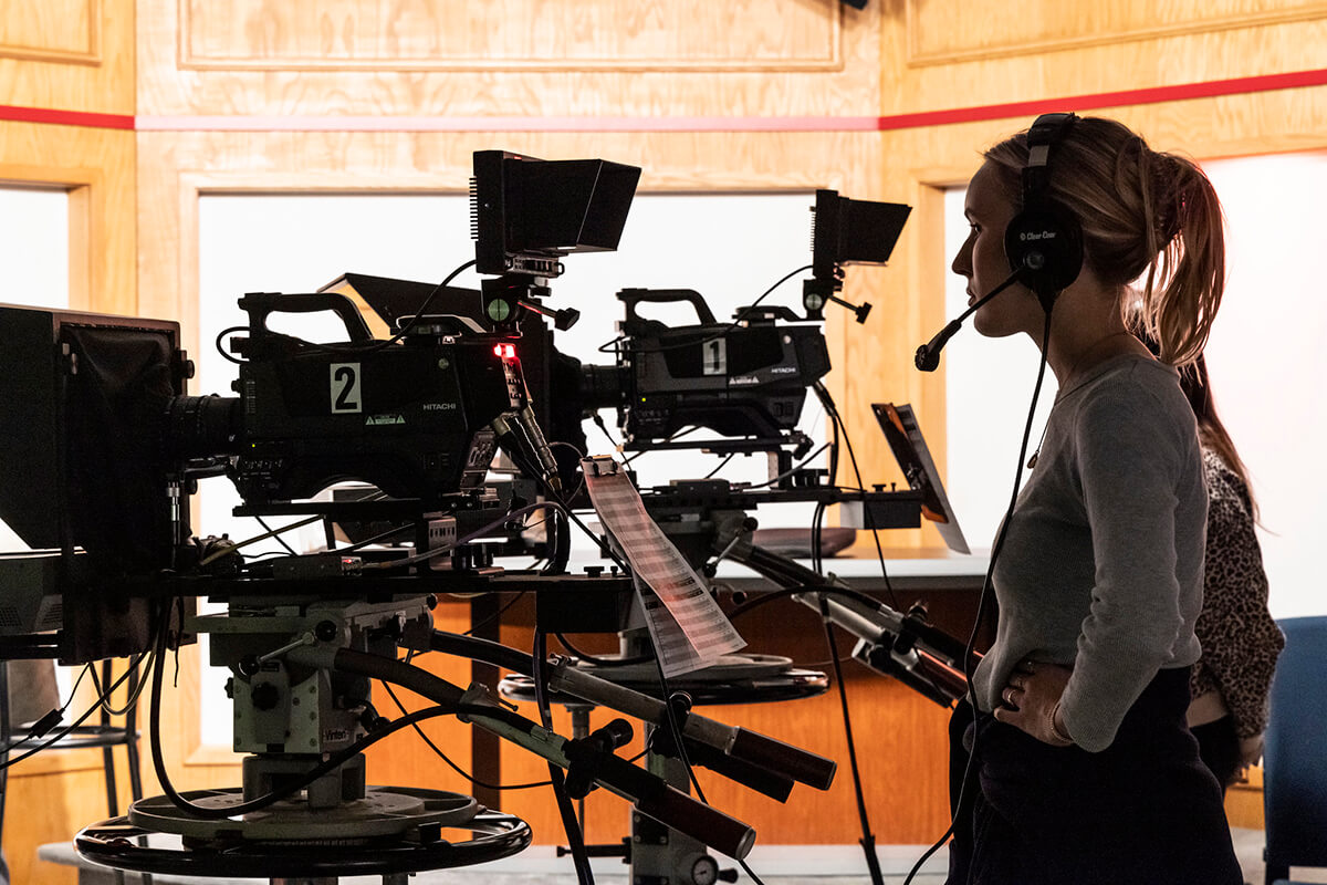 female student working large news camera in studio