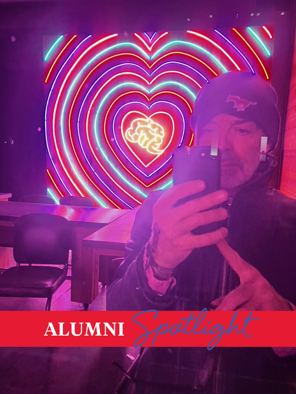 Art alum Michael Matson poses with a neon sign