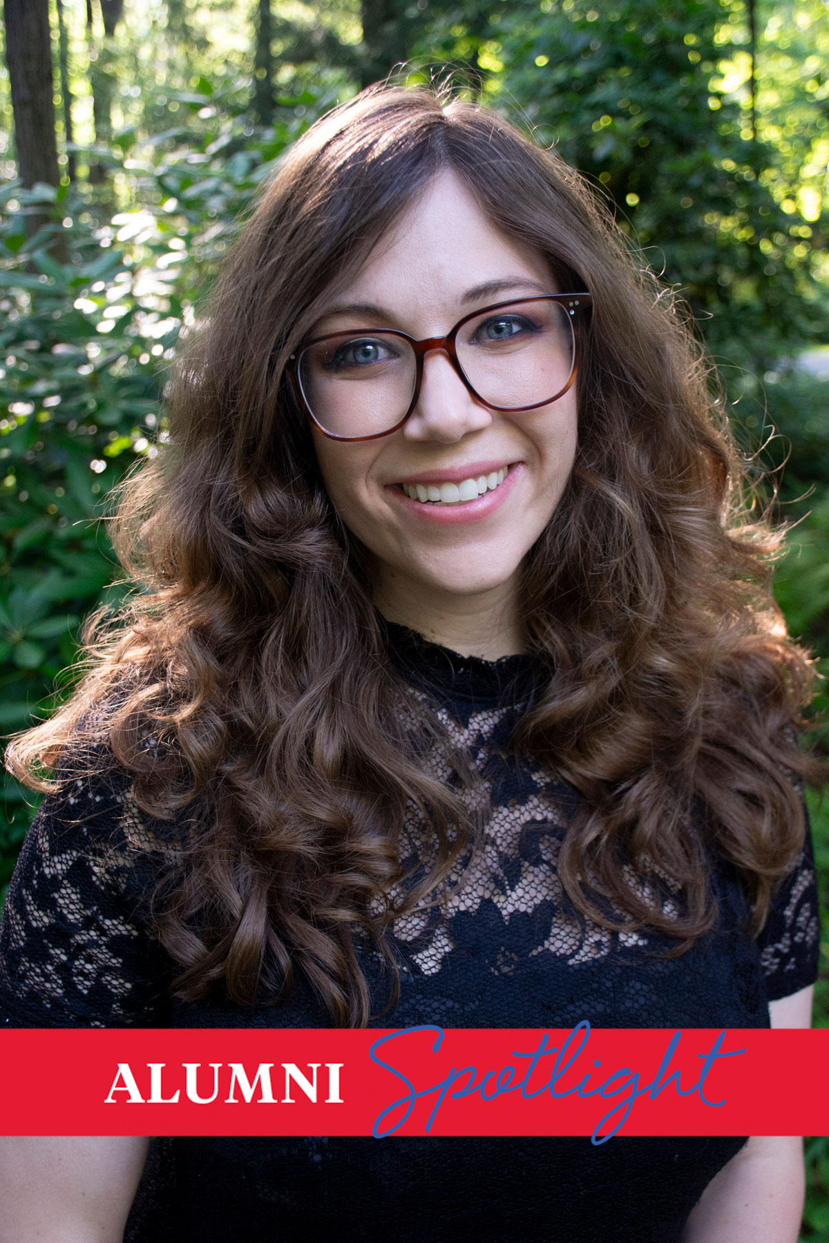 Art alum Beth Greenleaf poses for a headshot photo in a black shirt and glasses