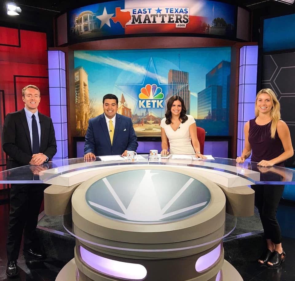 Journalism alum Cynthia McLaughlin poses behind an anchor desk with fellow anchors at KETK.