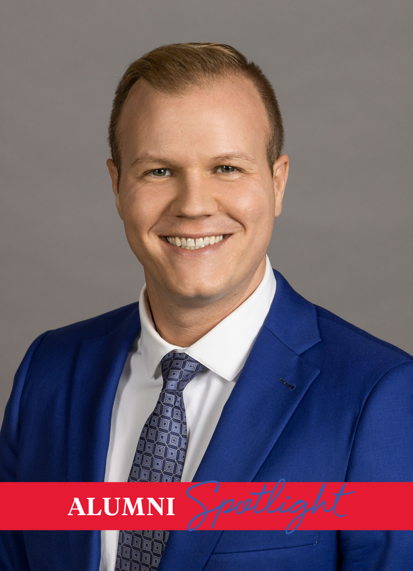 M.A./MBA alum Greg Oertel poses for a headshot in a blue suit