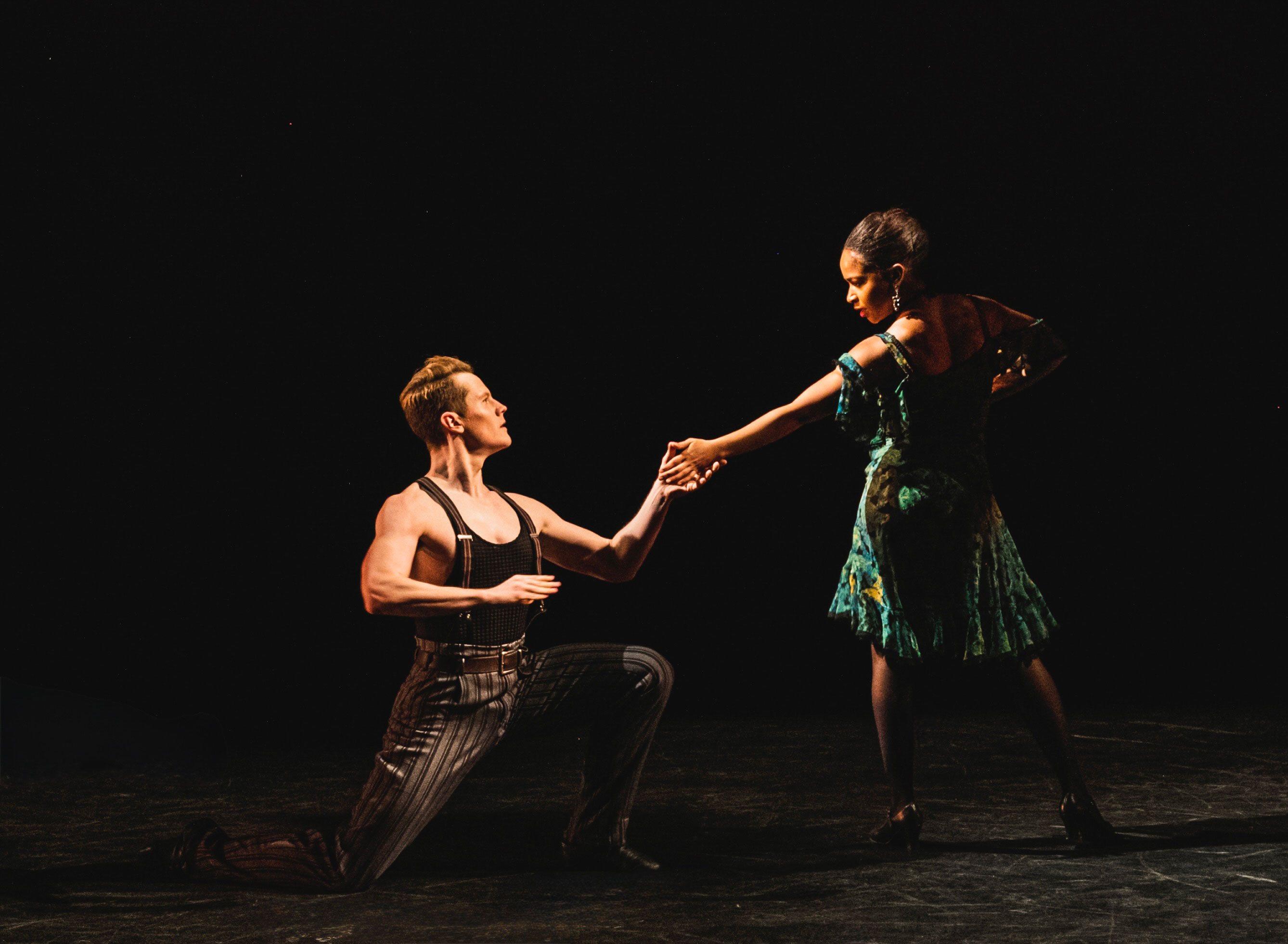Dance alum Lee Duveneck kneels on stage during a production
