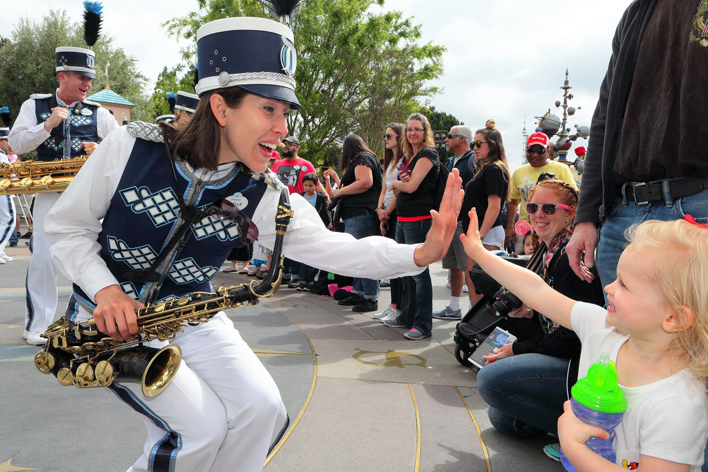 Alum Noelle Fabian Dragon high fives a child while marching in a band