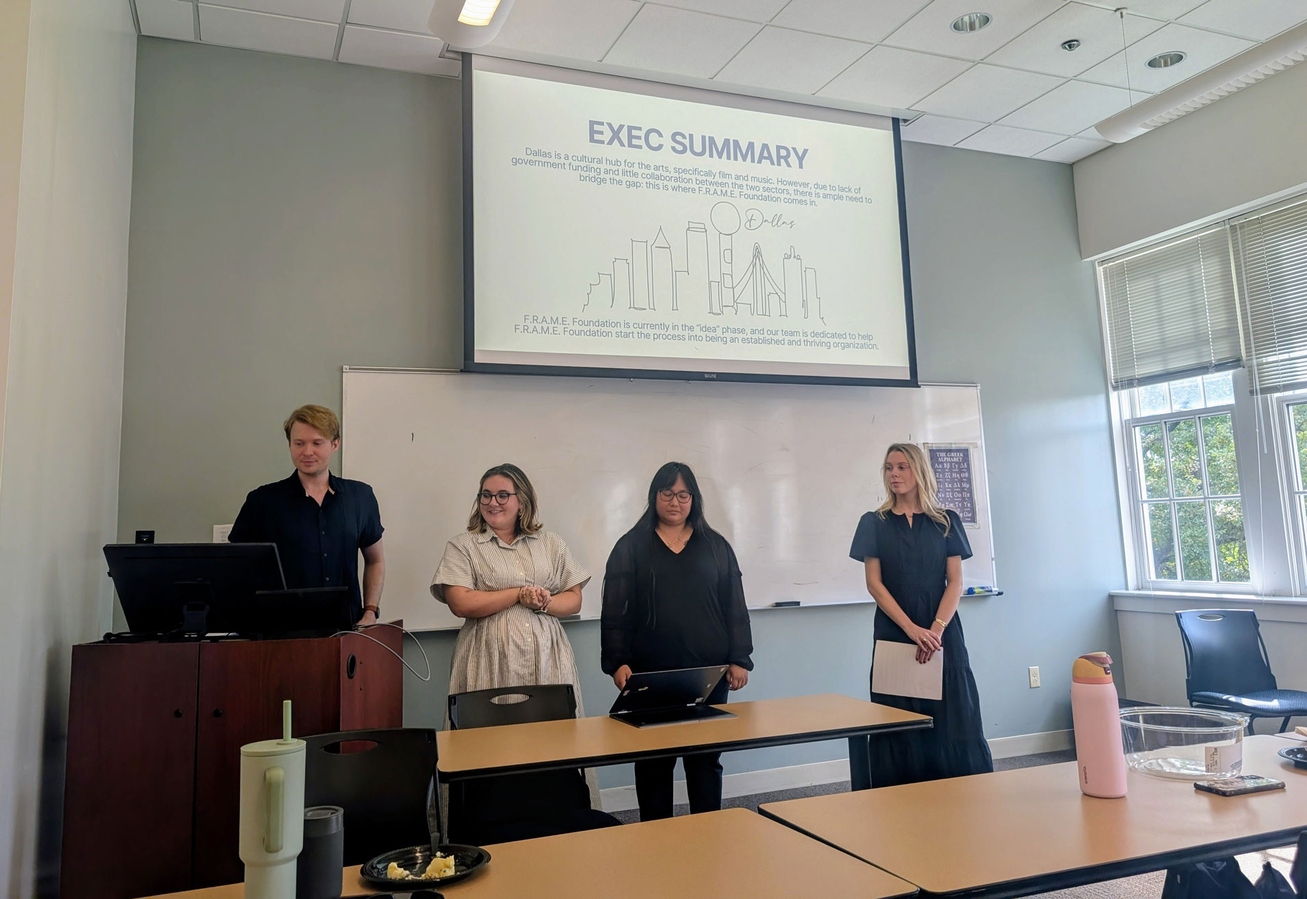 Students stand at the front of a classroom presenting to an organization.