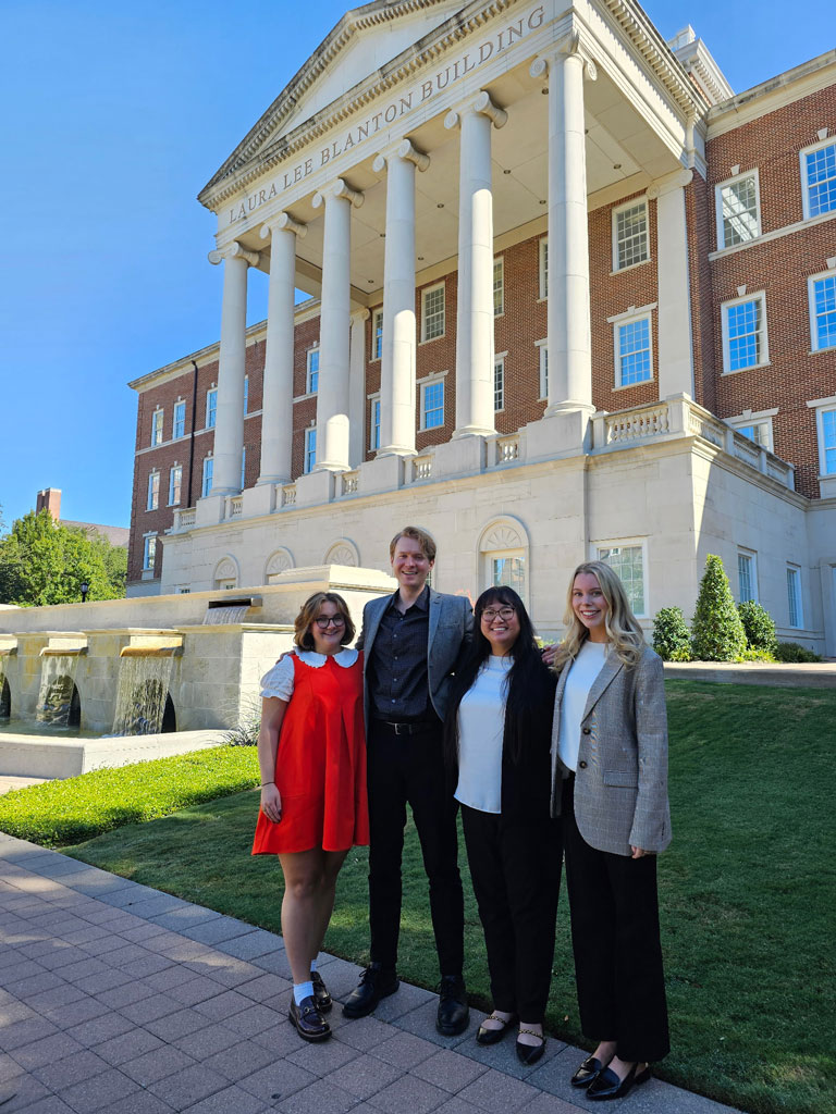 Foundations of Arts and Nonprofit Leadership cohort of four students pose on campus in front of Dallas Hall.