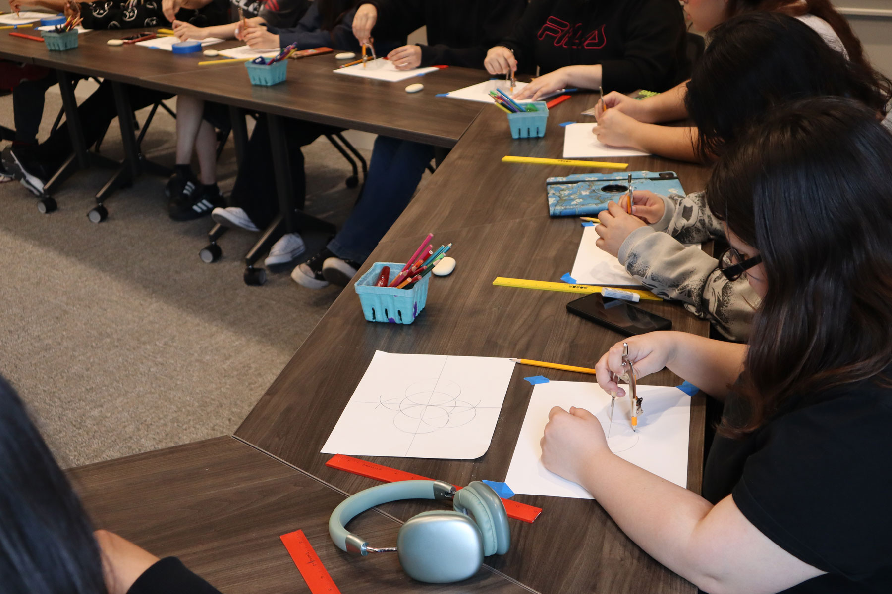 Close up of students using compasses to make geometric art patterns
