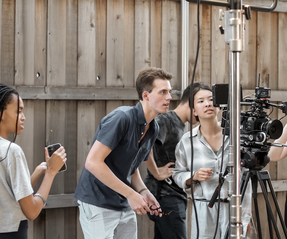 Film alum Ryder McNeal on the set of a student production operating a camera.