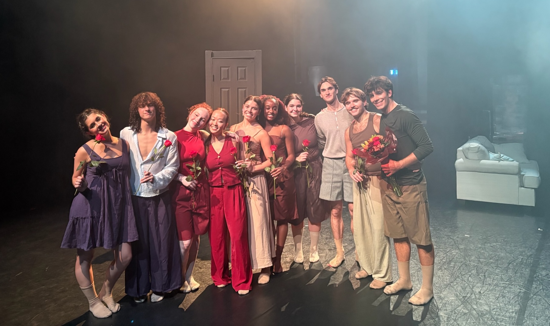 Ten dancers pose with flowers after finishing their show
